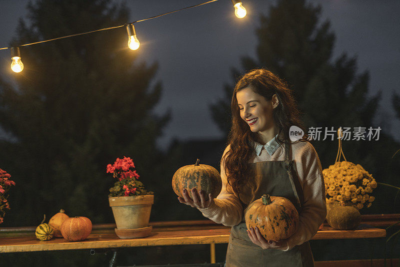 Woman enjoying in autumn, holding pumpkin and taking care of plants